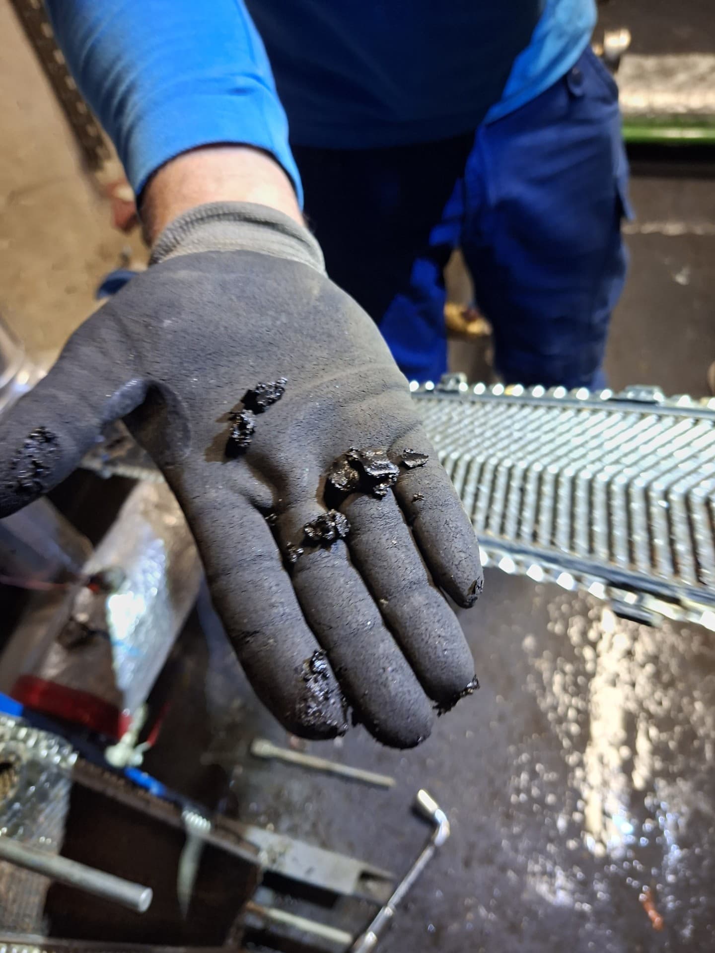 Gant de technicien recouvert de dépôts de boue noire extraits  de l'échangeur primaire d'une chaufferie de copropriété à Torcy  – LC THERMIC