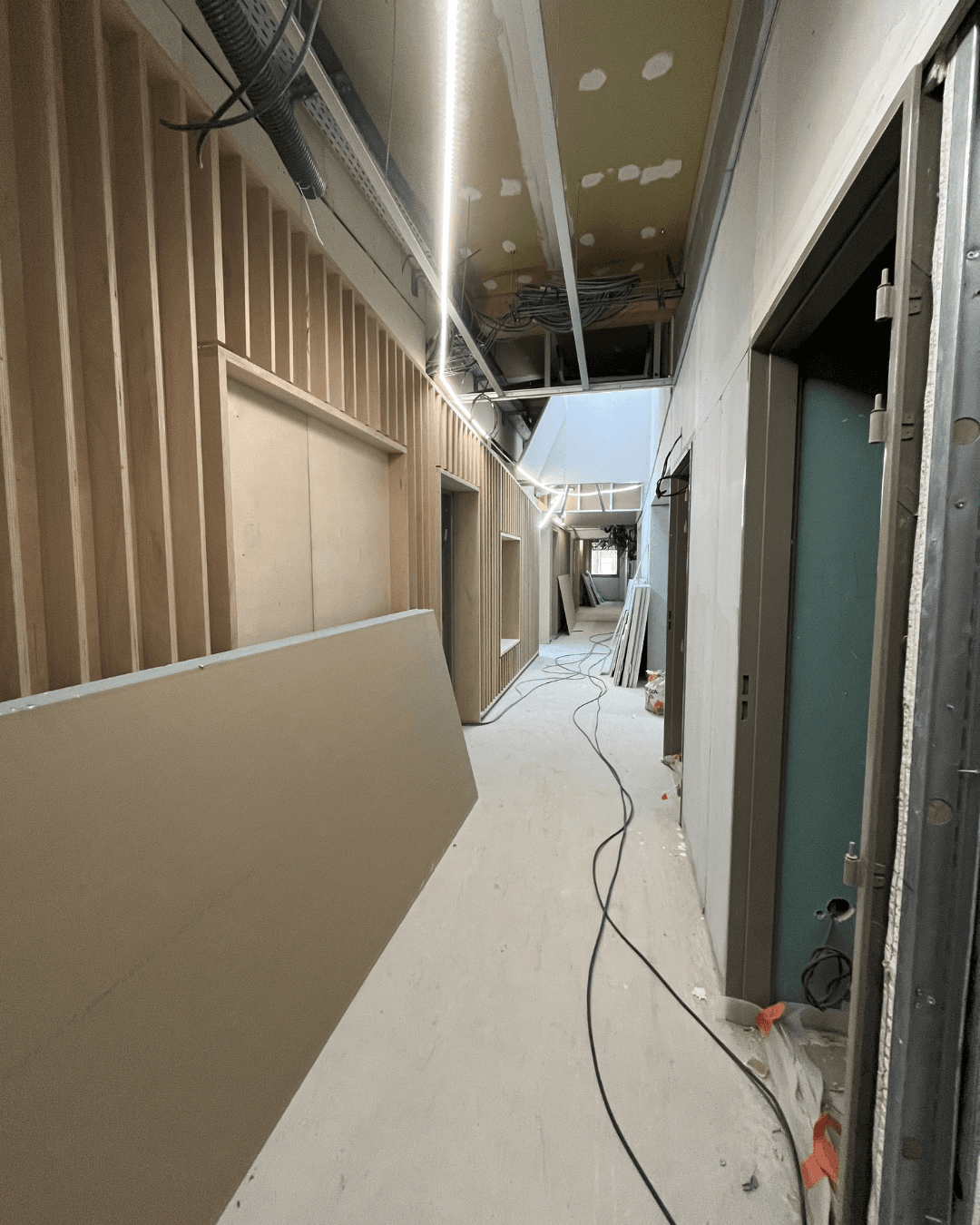 Couloir de l'UEHC de Rosny-sous-Bois avec réseaux CVC  en faux plafond et bardage bois en cours de pose  – Chantier Lot 4 LC THERMIC